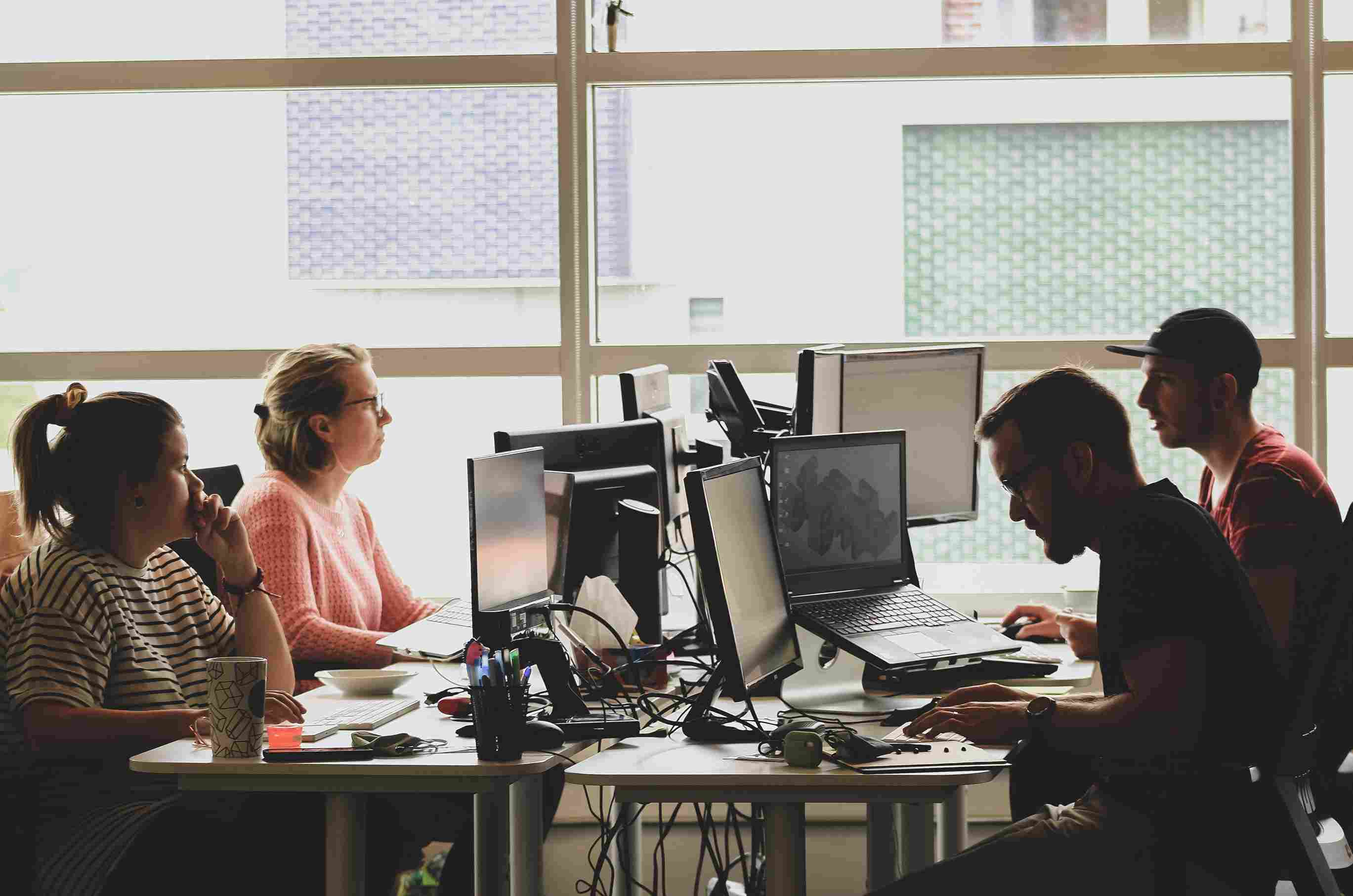 Employees at a table working on desktops