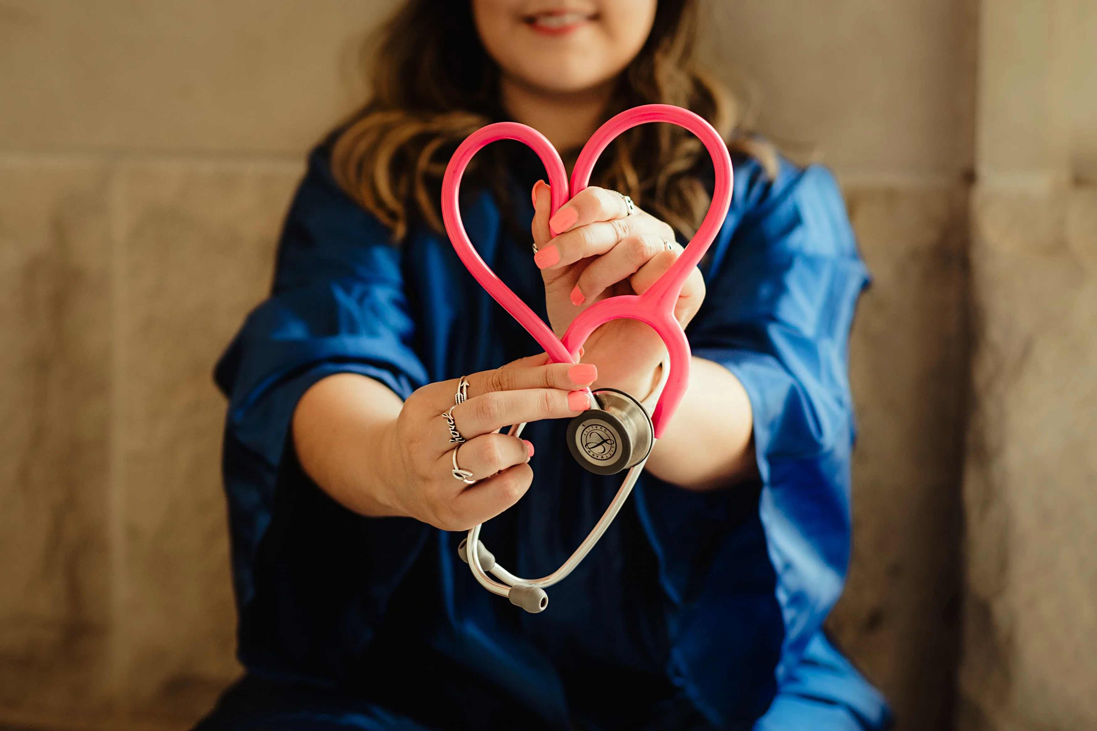 Healthcare worker holding pink stethoscope.